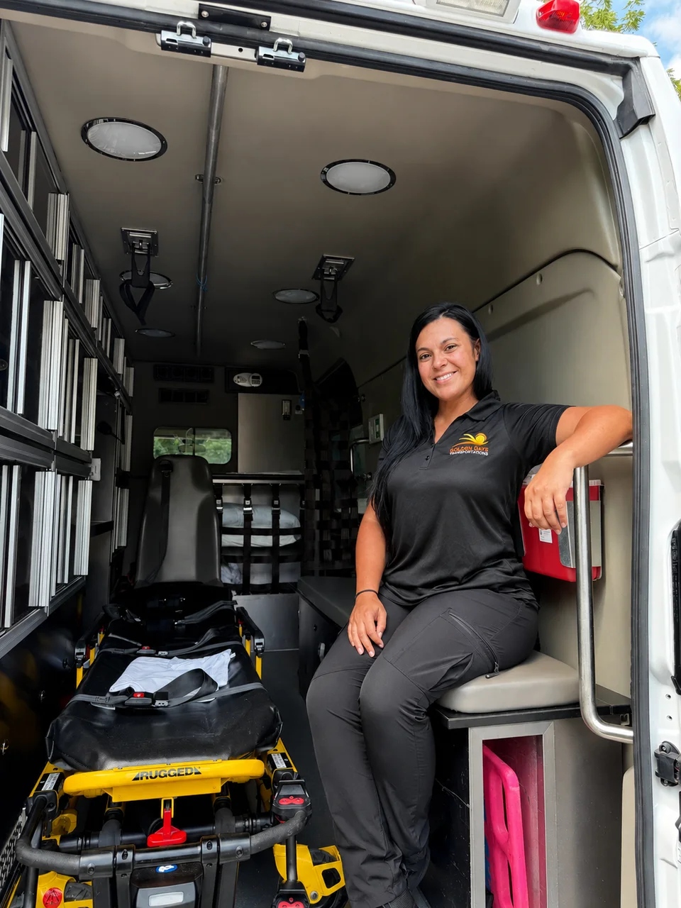 Golden Days team member seated inside the ambulance beside the stretcher